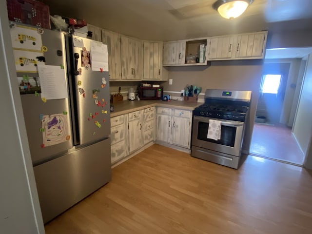 kitchen featuring white cabinetry, stainless steel appliances, light countertops, and light wood-style floors