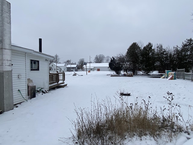 yard layered in snow with a playground and a deck