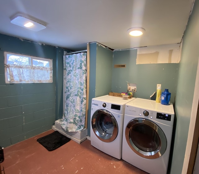 clothes washing area featuring laundry area, concrete block wall, and washer and clothes dryer