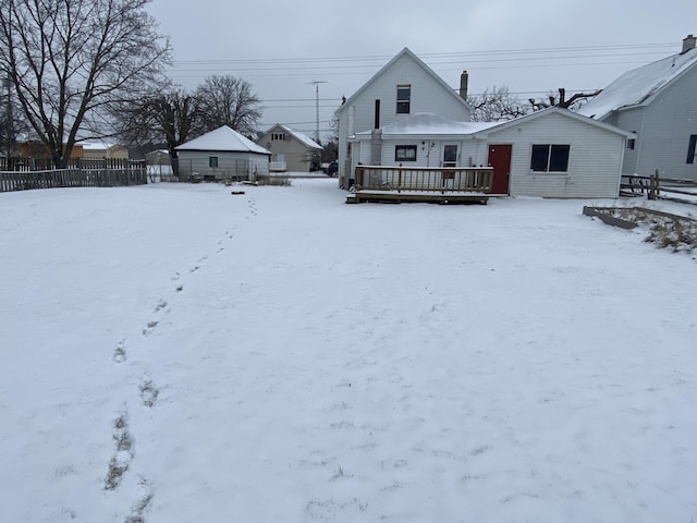 snow covered rear of property featuring a wooden deck and fence