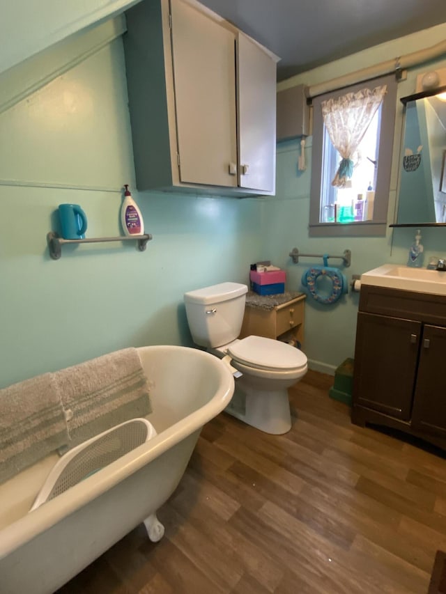 bathroom with vanity, a soaking tub, toilet, and wood finished floors