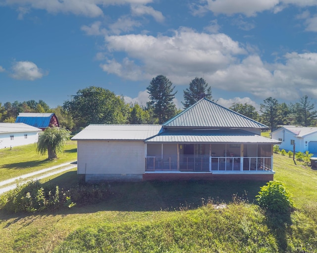 back of property with a lawn, a sunroom, and metal roof