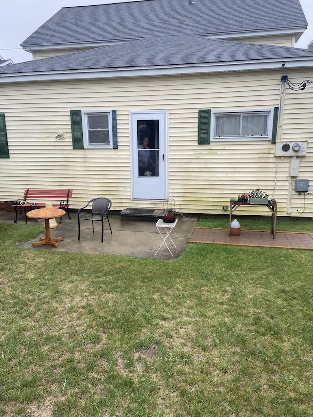 back of property featuring a patio, a lawn, and roof with shingles