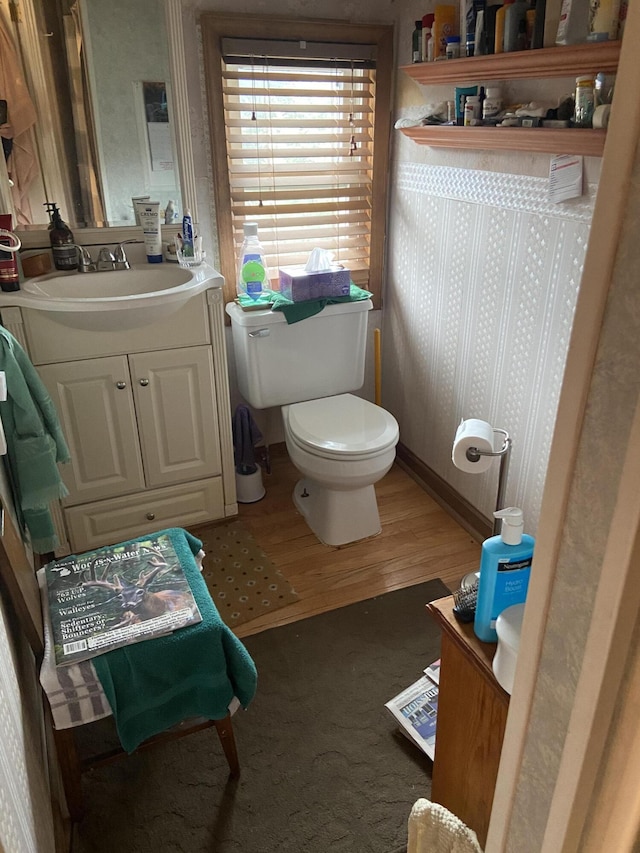 half bathroom featuring toilet, vanity, and wood finished floors