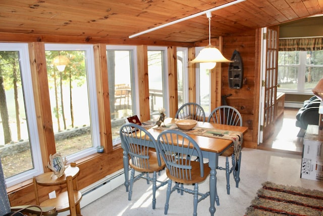 dining space featuring a baseboard radiator, wooden ceiling, and wood walls