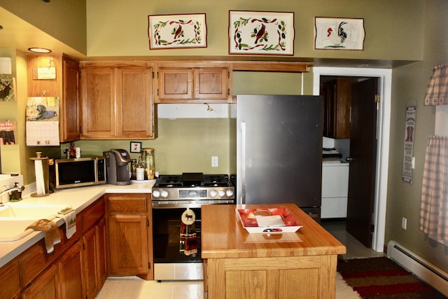 kitchen with a sink, washer / clothes dryer, a kitchen island, stainless steel appliances, and baseboard heating