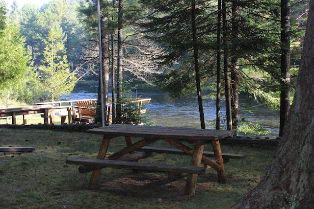 exterior space featuring a forest view, a water view, and a boat dock