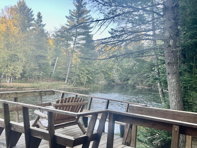 view of dock with a forest view and a water view