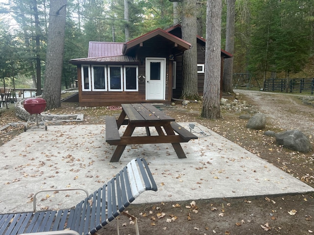 rear view of house with a patio area, a view of trees, metal roof, and fence