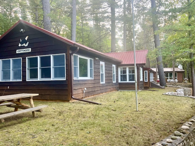 view of side of home featuring metal roof and a lawn