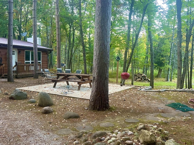 view of yard with a forest view, a deck, and a patio area