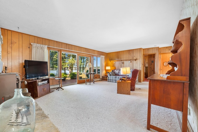 living area with a baseboard heating unit, light carpet, and wooden walls