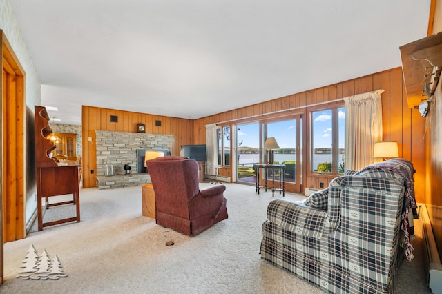 carpeted living area with a baseboard heating unit, wooden walls, and a fireplace