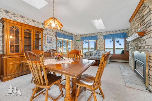 dining area featuring light colored carpet, a skylight, a fireplace, and wallpapered walls