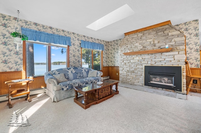 living room featuring a skylight, a wainscoted wall, wallpapered walls, and a baseboard heating unit