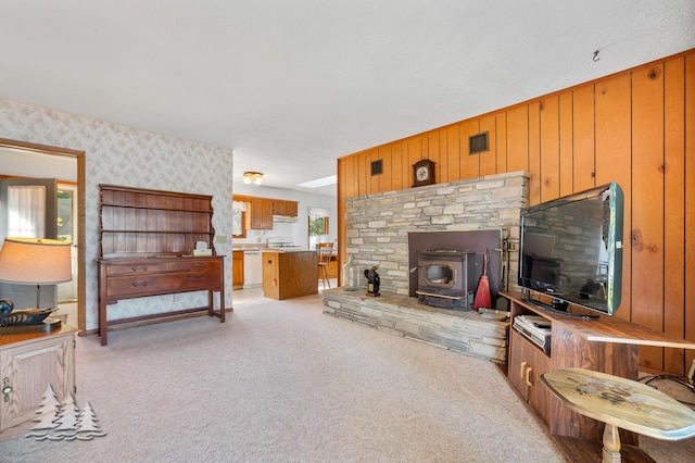 living room featuring light carpet and a wood stove