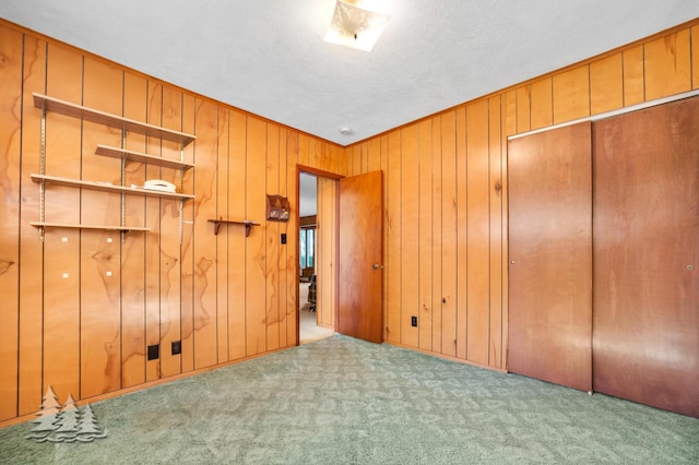 unfurnished bedroom featuring carpet, a closet, and wood walls