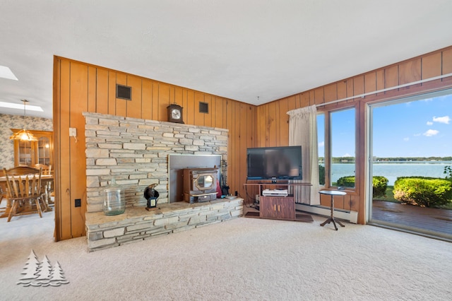 living room featuring a baseboard heating unit, a wood stove, visible vents, and carpet floors