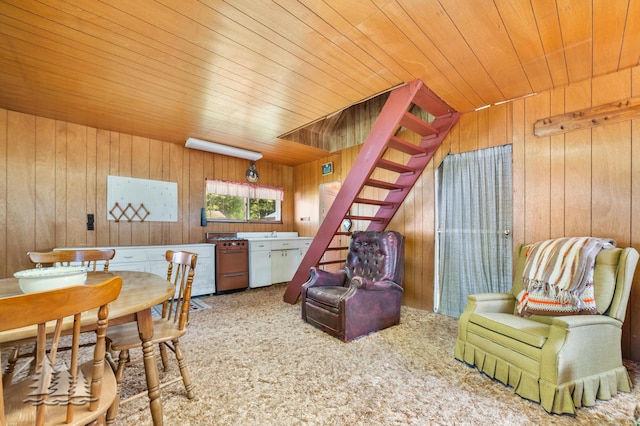 dining room with stairs, carpet flooring, wood ceiling, and wood walls