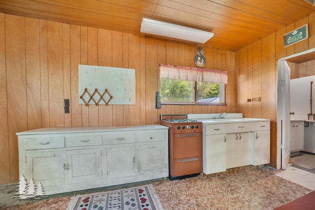 kitchen featuring range with gas cooktop, wooden walls, white cabinets, light countertops, and wood ceiling