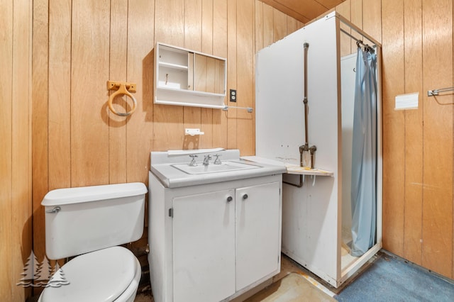 bathroom with wood walls, a stall shower, vanity, and toilet