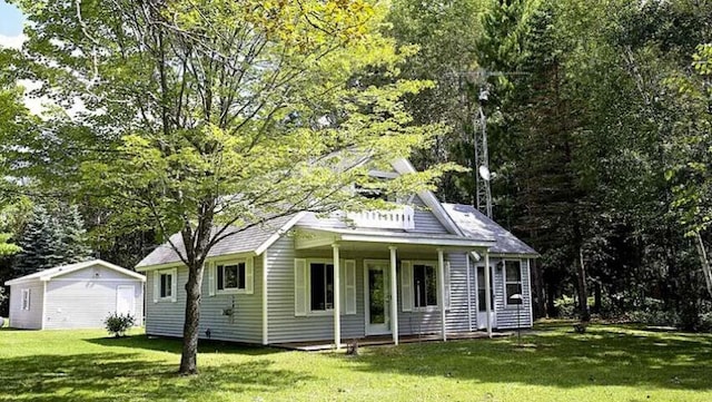 view of front of home with an outbuilding, covered porch, and a front yard