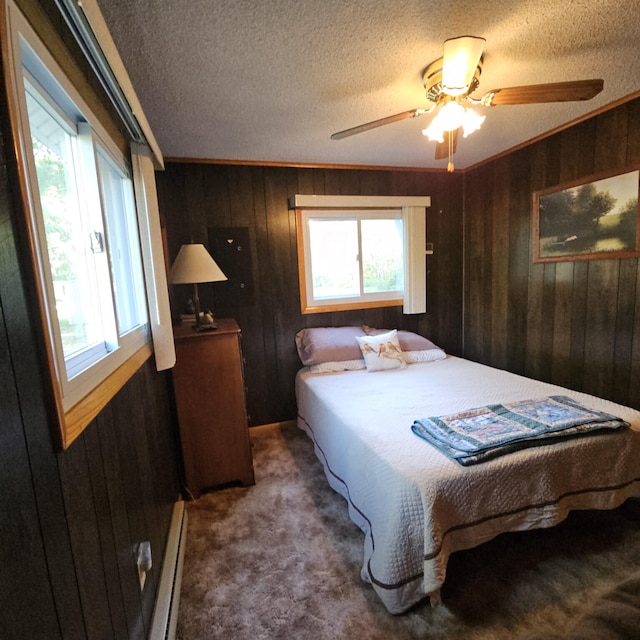 bedroom featuring baseboard heating, multiple windows, wood walls, and carpet floors