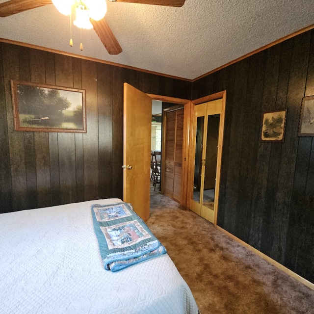 bedroom featuring crown molding, wooden walls, carpet flooring, and a textured ceiling