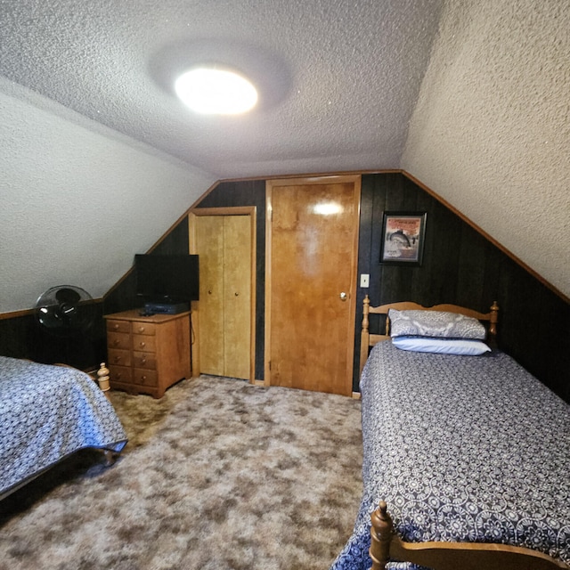 carpeted bedroom with a textured ceiling and vaulted ceiling