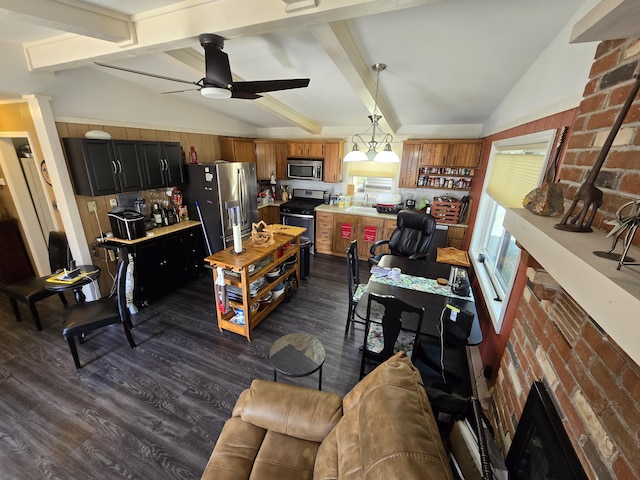 interior space featuring dark wood finished floors, light countertops, lofted ceiling with beams, appliances with stainless steel finishes, and hanging light fixtures