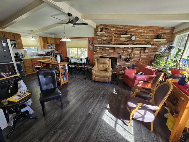 living area with a brick fireplace, brick wall, dark wood finished floors, lofted ceiling with beams, and a ceiling fan