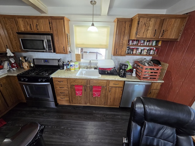 kitchen with beamed ceiling, brown cabinets, appliances with stainless steel finishes, and a sink