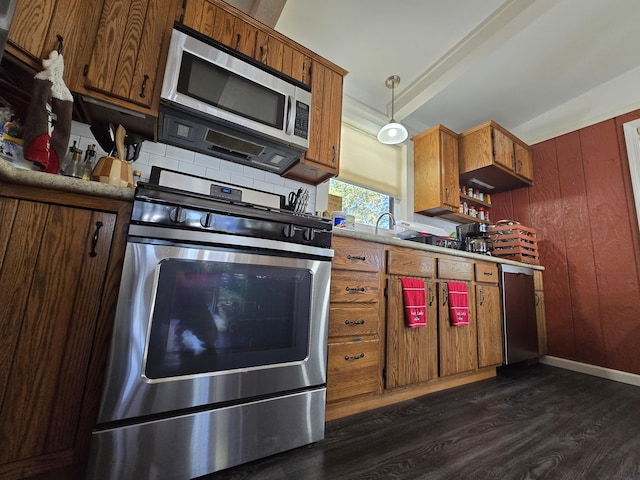 kitchen featuring dark wood-type flooring, decorative light fixtures, stainless steel appliances, light countertops, and decorative backsplash