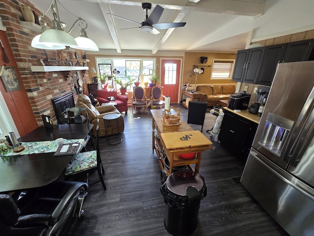 kitchen featuring dark wood finished floors, beam ceiling, a fireplace, stainless steel refrigerator with ice dispenser, and open floor plan