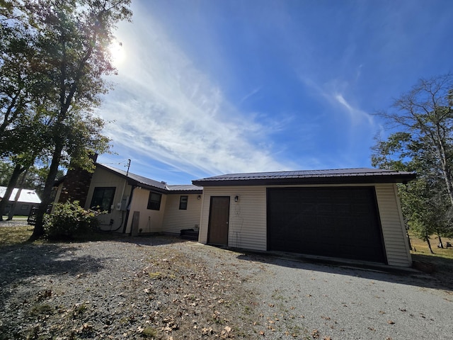 ranch-style home featuring driveway, metal roof, and an attached garage