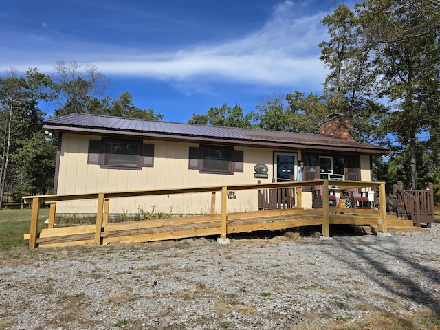 view of front of house featuring a wooden deck, metal roof, and a chimney