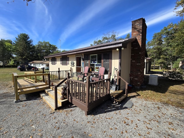 rear view of property with a chimney and a deck