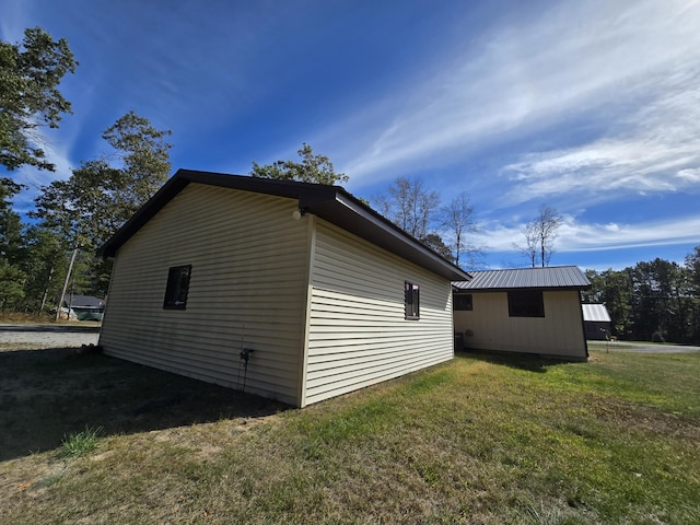 view of side of home featuring metal roof and a lawn