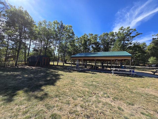 view of community with a gazebo, a storage unit, a lawn, and an outdoor structure