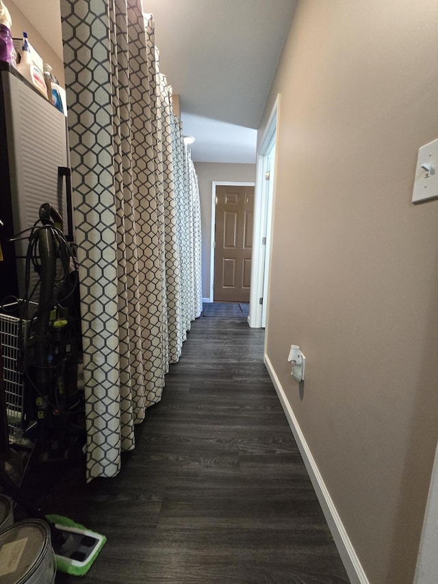 hallway featuring baseboards and dark wood-style flooring