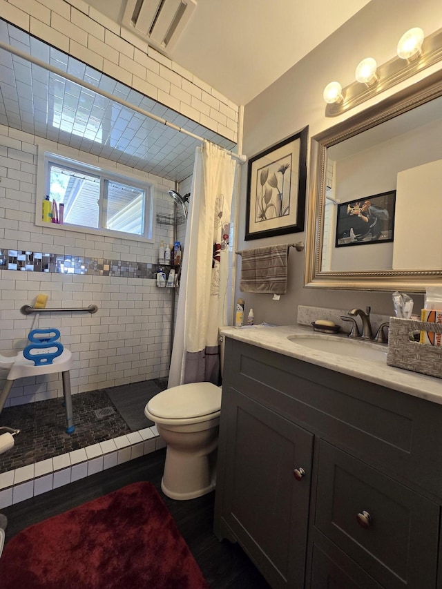 bathroom with vanity, toilet, and tiled shower