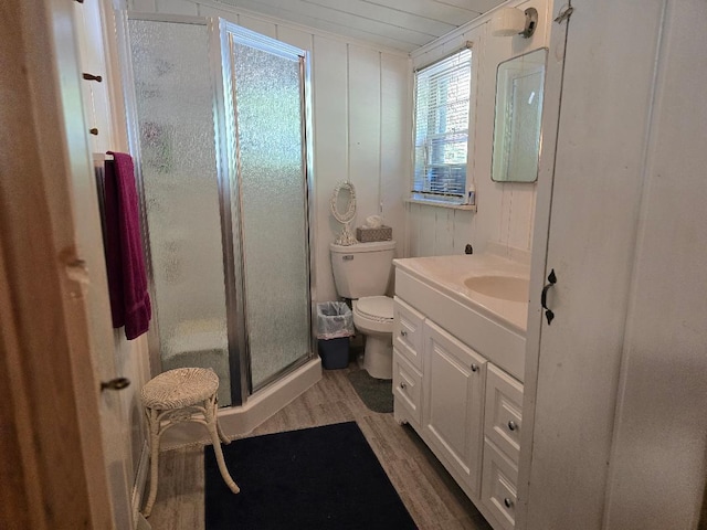 bathroom with wood finished floors, toilet, a stall shower, and vanity