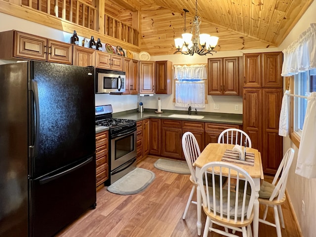 kitchen with brown cabinetry, light wood-style flooring, a sink, stainless steel appliances, and dark countertops