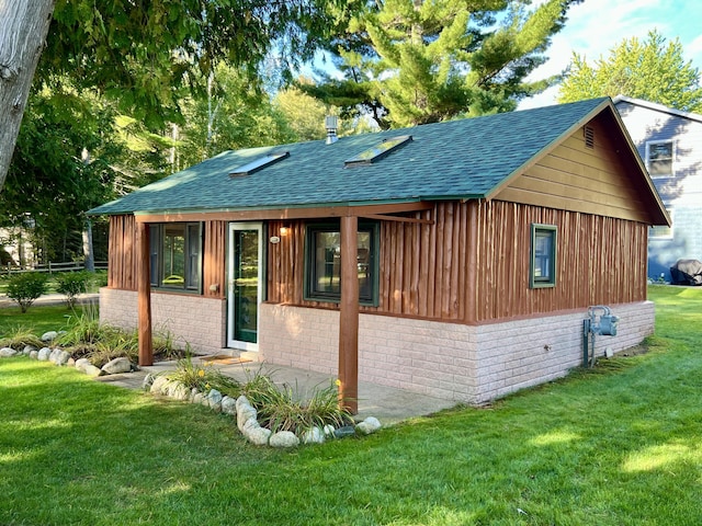 back of property featuring a lawn, roof with shingles, and brick siding