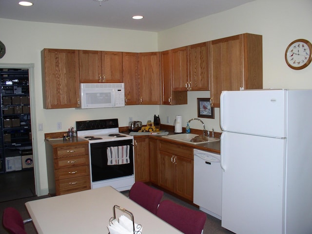 kitchen with a sink, white appliances, recessed lighting, and brown cabinetry