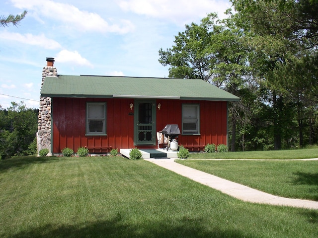 view of front of home featuring board and batten siding, a chimney, and a front yard