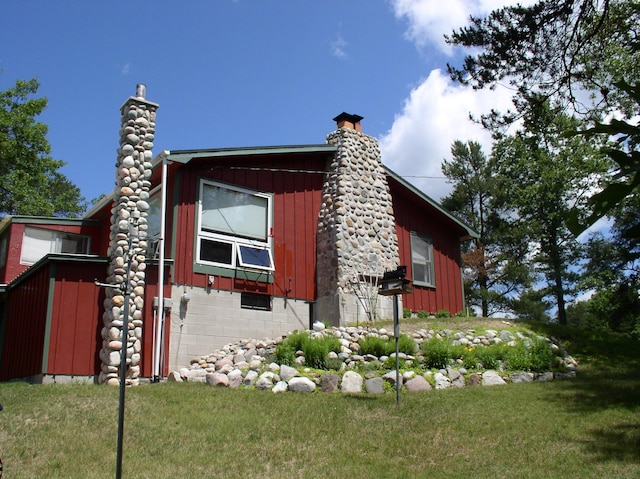 view of side of property with board and batten siding, a chimney, and a yard