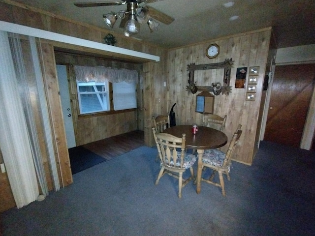 dining room featuring wood walls, ceiling fan, and carpet floors