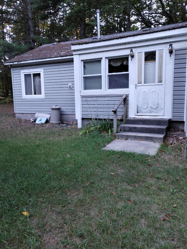 exterior space with entry steps and a lawn