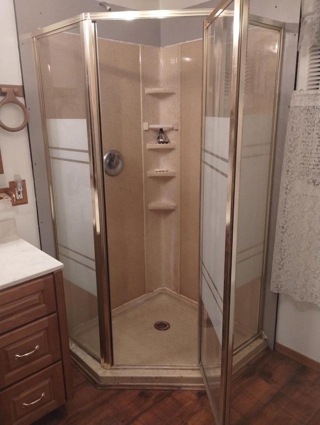 bathroom featuring vanity, wood finished floors, and a stall shower